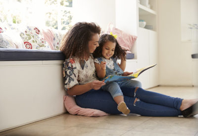 Woman and child reading book inside and smiling