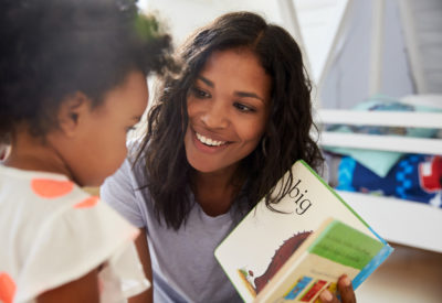 Woman smiling at boy, who is reading a book